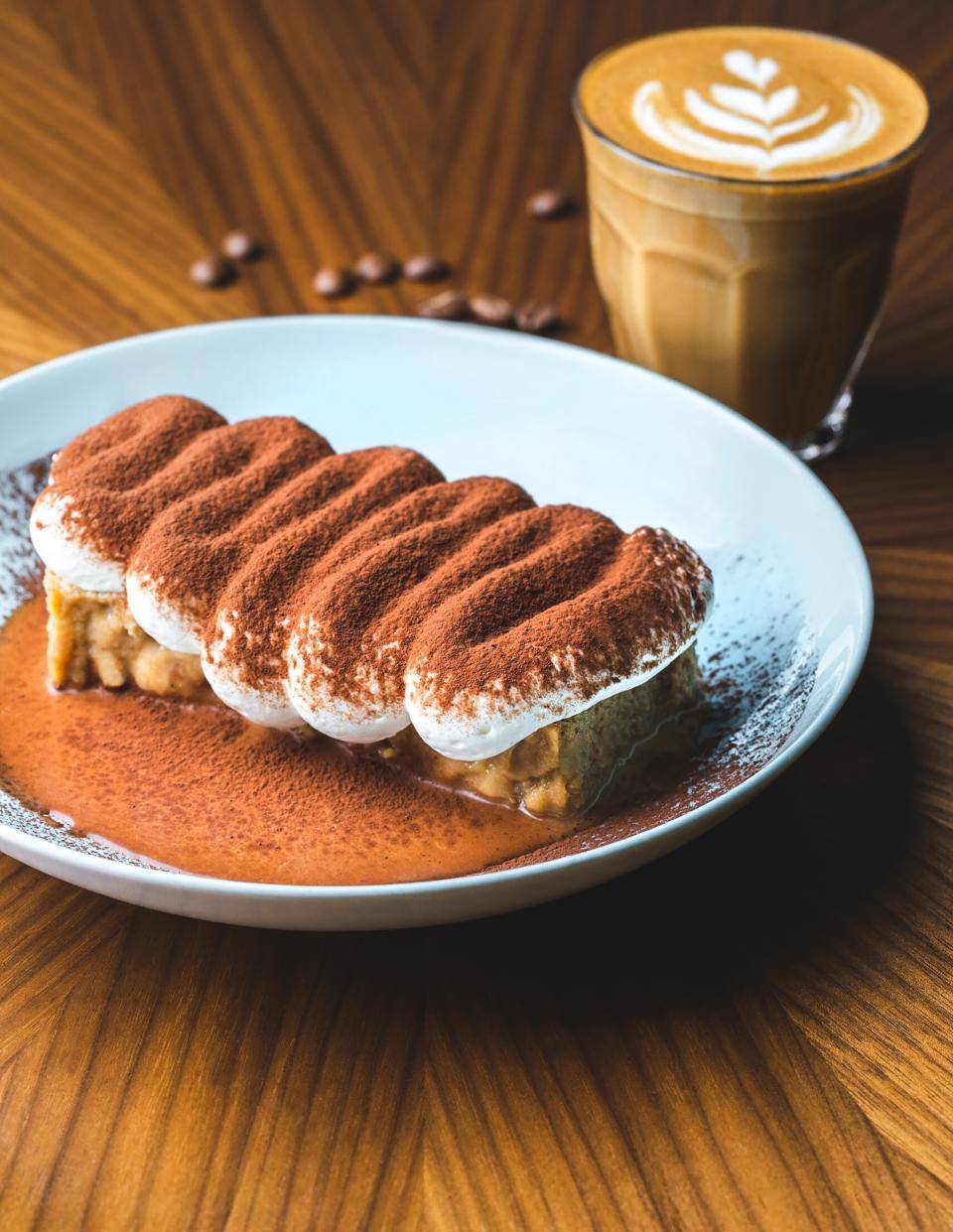 sobremesa empratada com cacau em pó em cima e copo de café ao funso