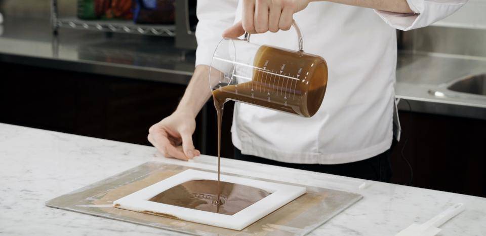 a chef pours ganache into a frame