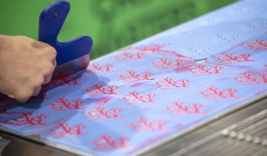 A chef's hand scraping a stencil to make delicate chocolate decor