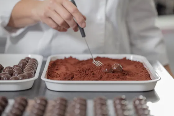 mão de chef empurrando massa de chocolate (rufas) no cacau em pó