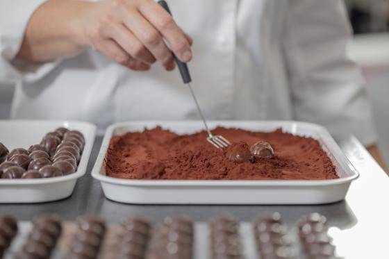 mão de chef empurrando massa de chocolate (rufas) no cacau em pó